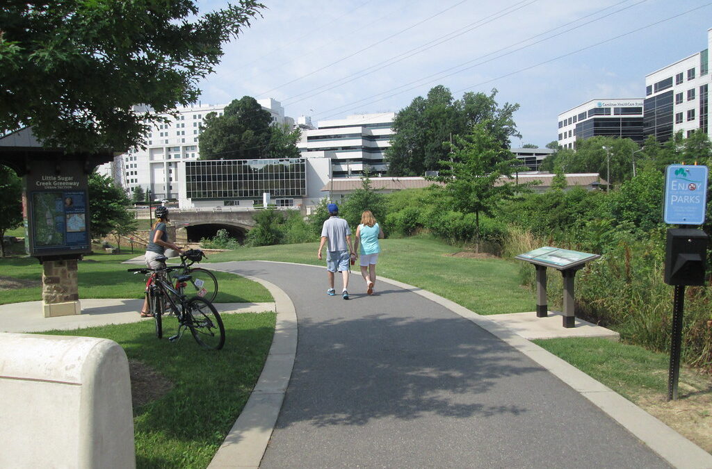 Couple walking and lady riding bike on the Little Sugar Creek Greenway in Charlotte NC