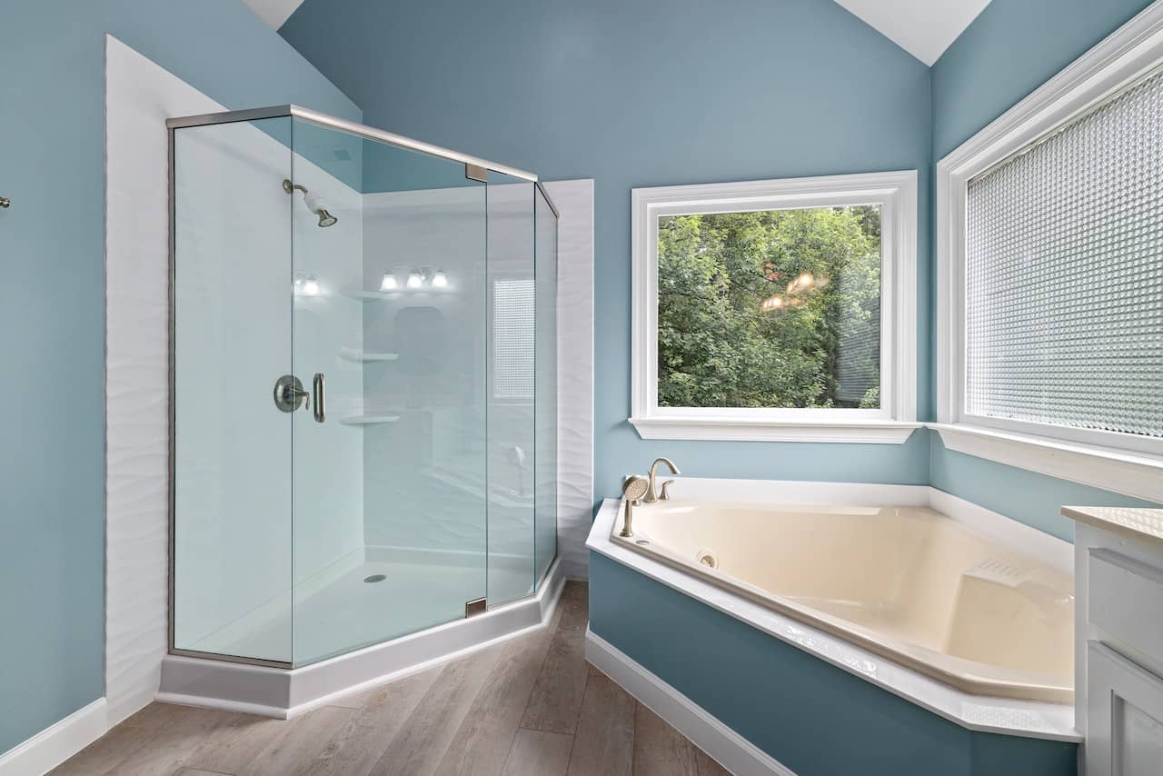 Light blue bathroom with glass shower and garden tub. Bathroom Remodeling Contractors Charlotte