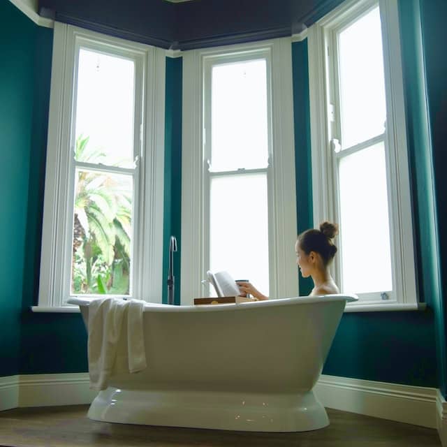 Woman sitting in tub in newly remodeled bathroom reading a book in Charlotte North Carolina.